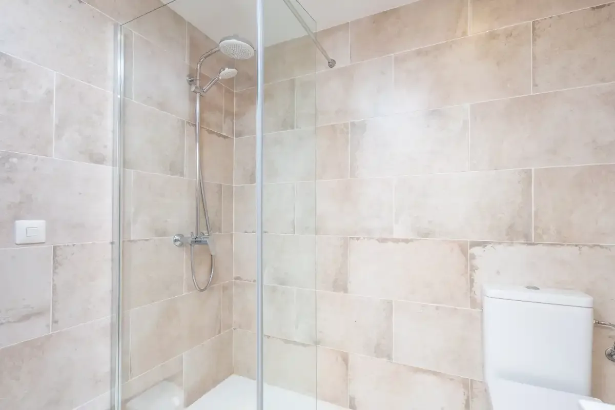 A tiled bathroom with a glass shower and a toilet.