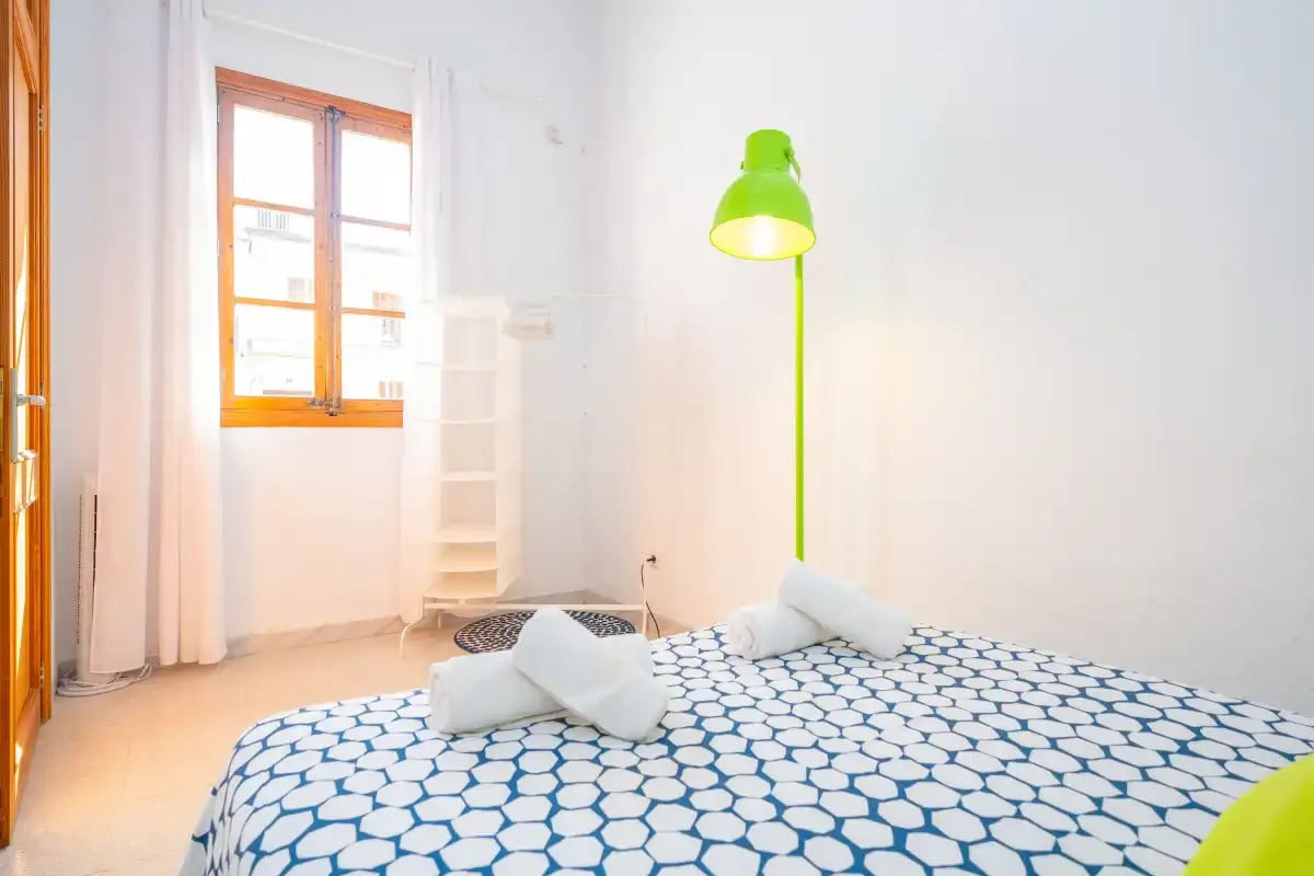 A bedroom with a bed covered by a blue-and-white patterned blanket.
