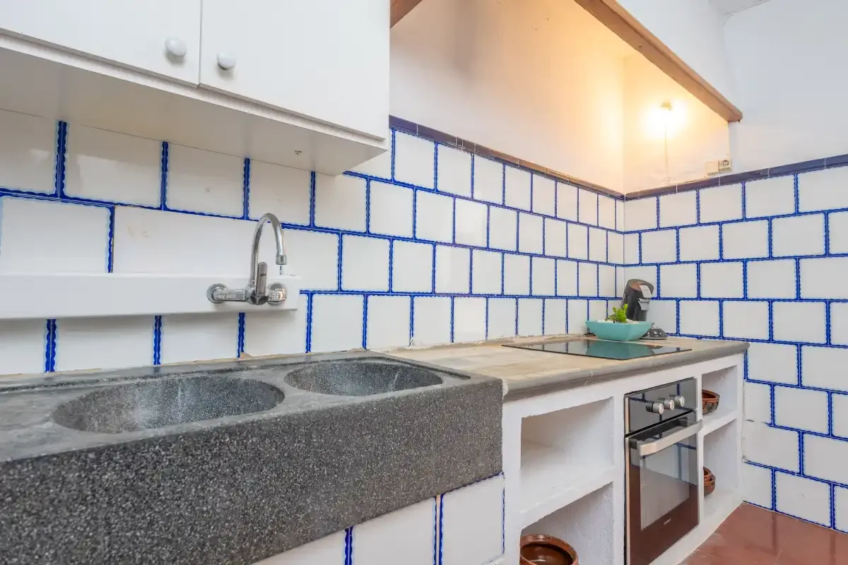 A tiled kitchen counter with a sink, faucet, and built-in oven.