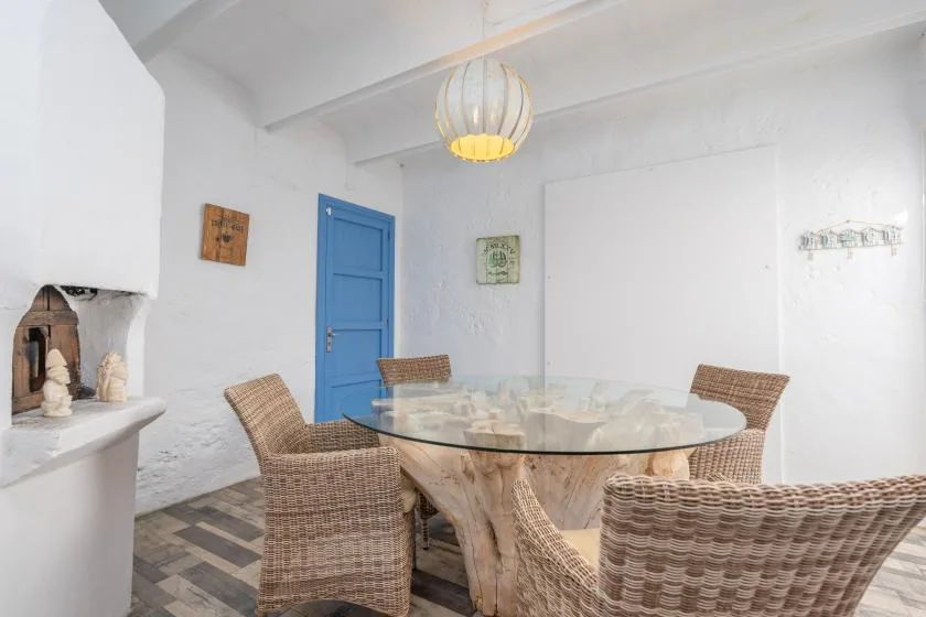 A bright dining room with a glass table and woven seating.