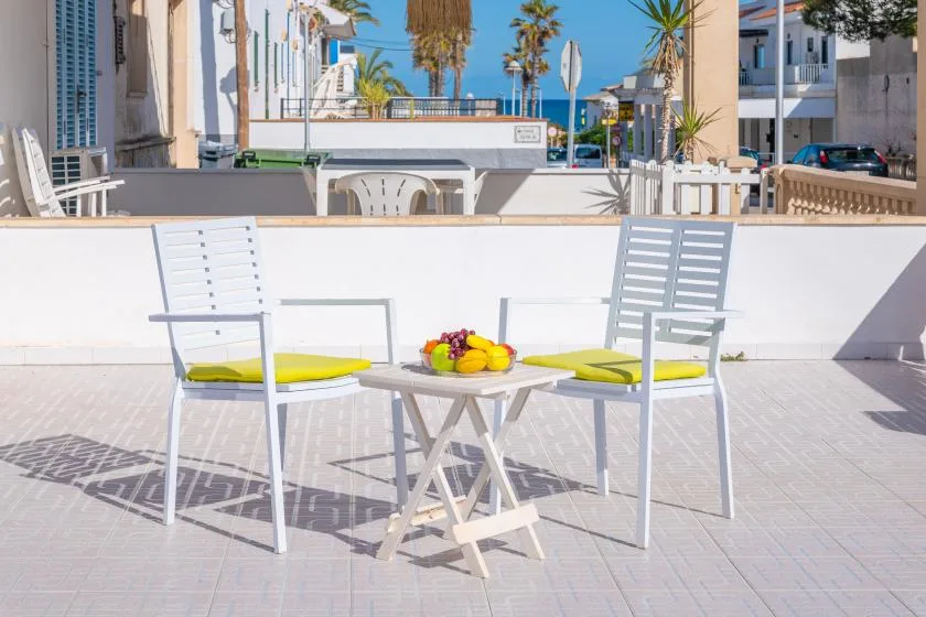 An outdoor patio seating area with a table holding a bowl of fruit.
