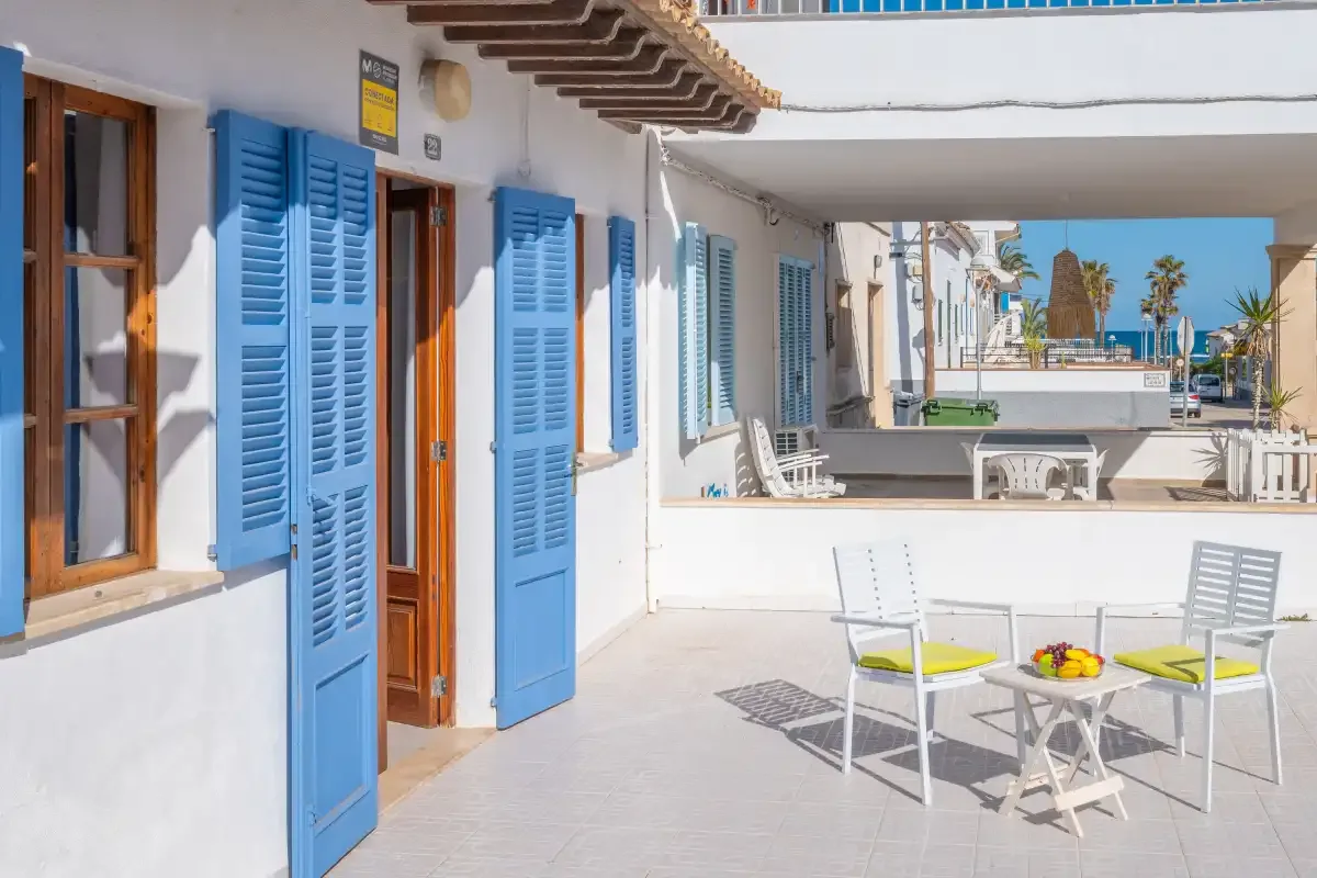 A sunny outdoor terrace with blue shutters and patio seating.