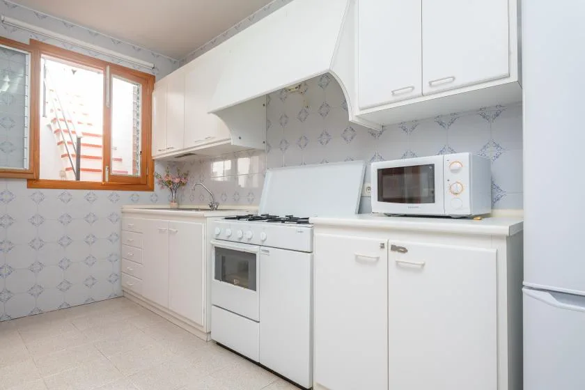 A bright kitchen with white cabinets, a stove, and a microwave.