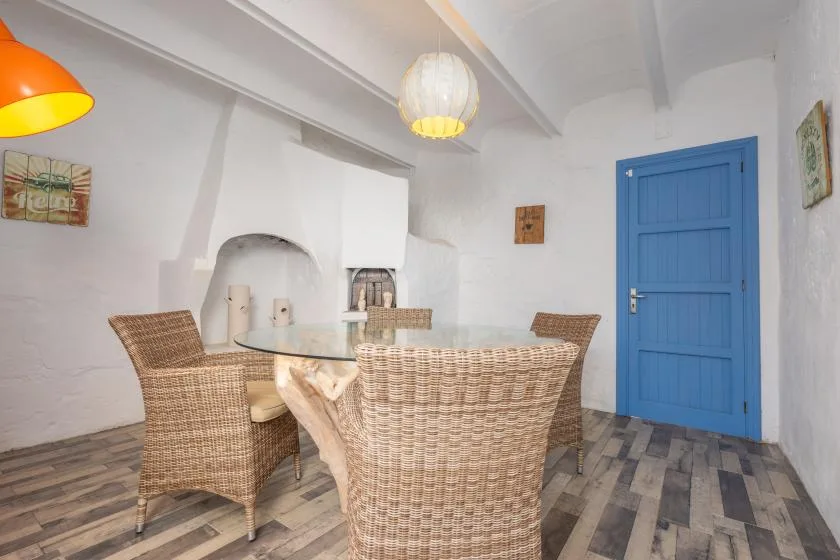 A dining area with woven seating around a table and a blue door.