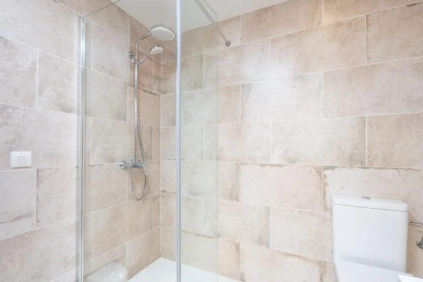 A tiled bathroom with a glass shower and toilet.