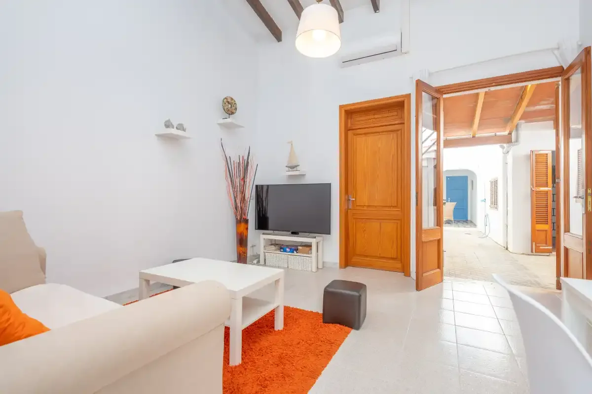 A bright living room with seating, a television, and an open doorway to a tiled area.