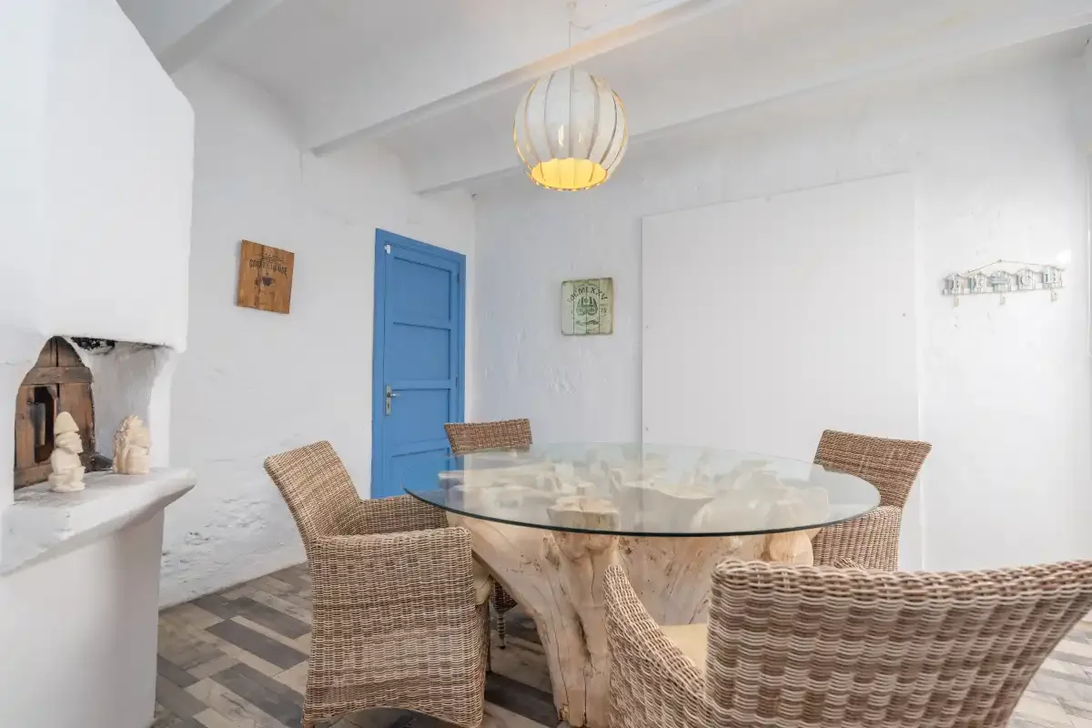 A dining area with a round glass table and woven seating.