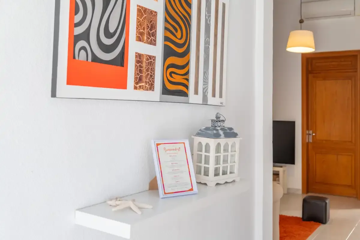 A white interior wall displays abstract artwork above a floating shelf.