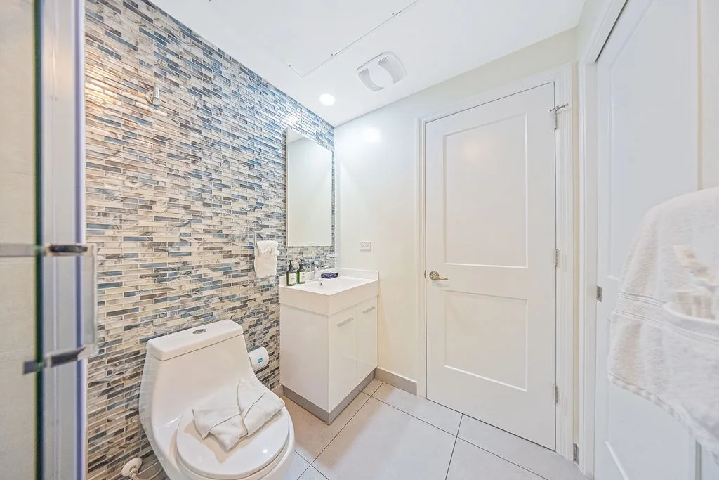 A bright bathroom with stylish mosaic tile and fresh towels awaits your arrival, offering a clean and welcoming space to refresh after your day of exploring.