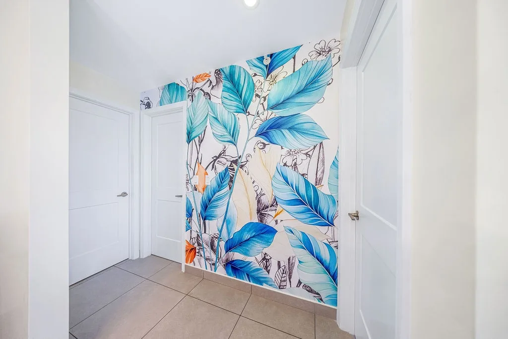 A vibrant tropical leaf mural brings a splash of color and personality to this welcoming entryway, setting the tone for your relaxing stay.