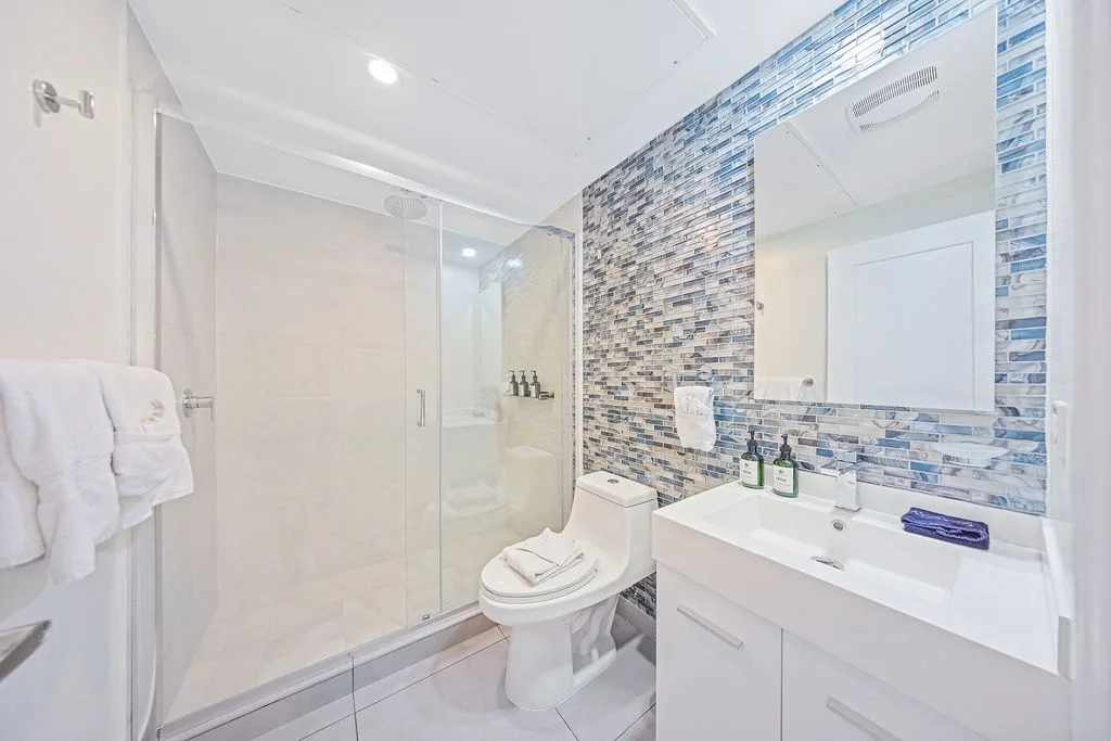 Refresh in your bright, modern bathroom with a walk-in shower and chic blue mosaic tilework that adds coastal charm to your morning routine.