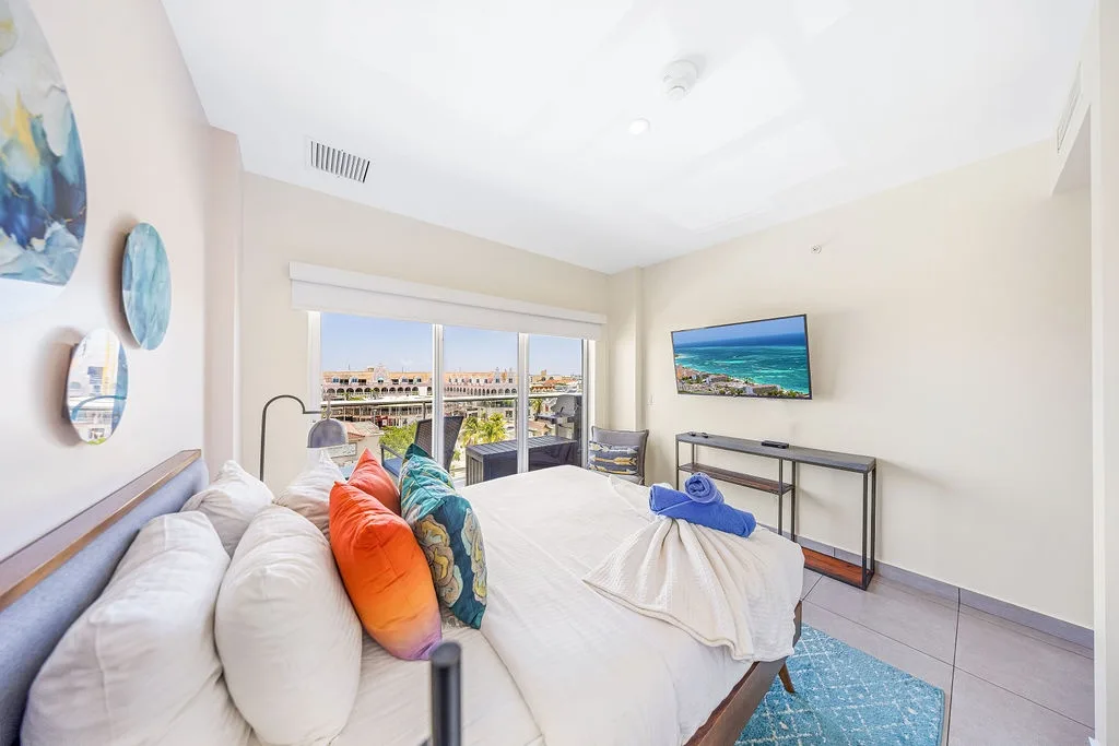 Wake up to sunlit comfort and colorful coastal accents. Floor-to-ceiling windows frame rooftop views and your private balcony. Entertainment awaits with your flat-screen TV and smart entertainment setup.