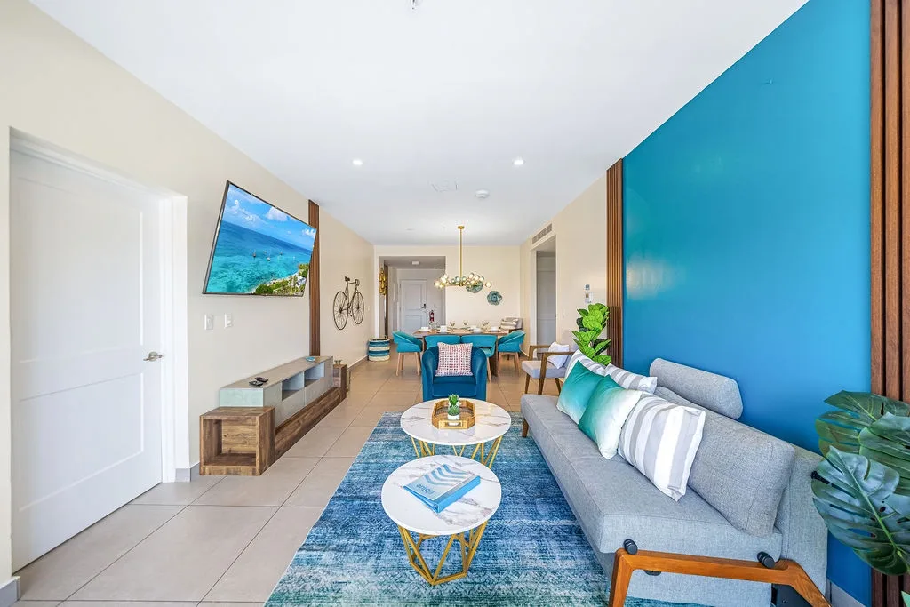 Your open-concept living and dining space welcomes you with coastal-inspired décor, comfortable seating, and vibrant pops of turquoise that capture the essence of a beachside getaway.