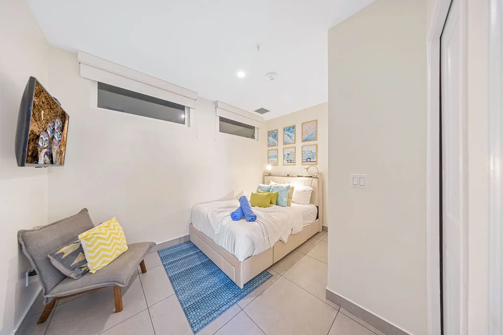 Your serene bedroom awaits with a plush bed, cheerful pops of color, and a cozy chair where you can unwind after exploring the area.