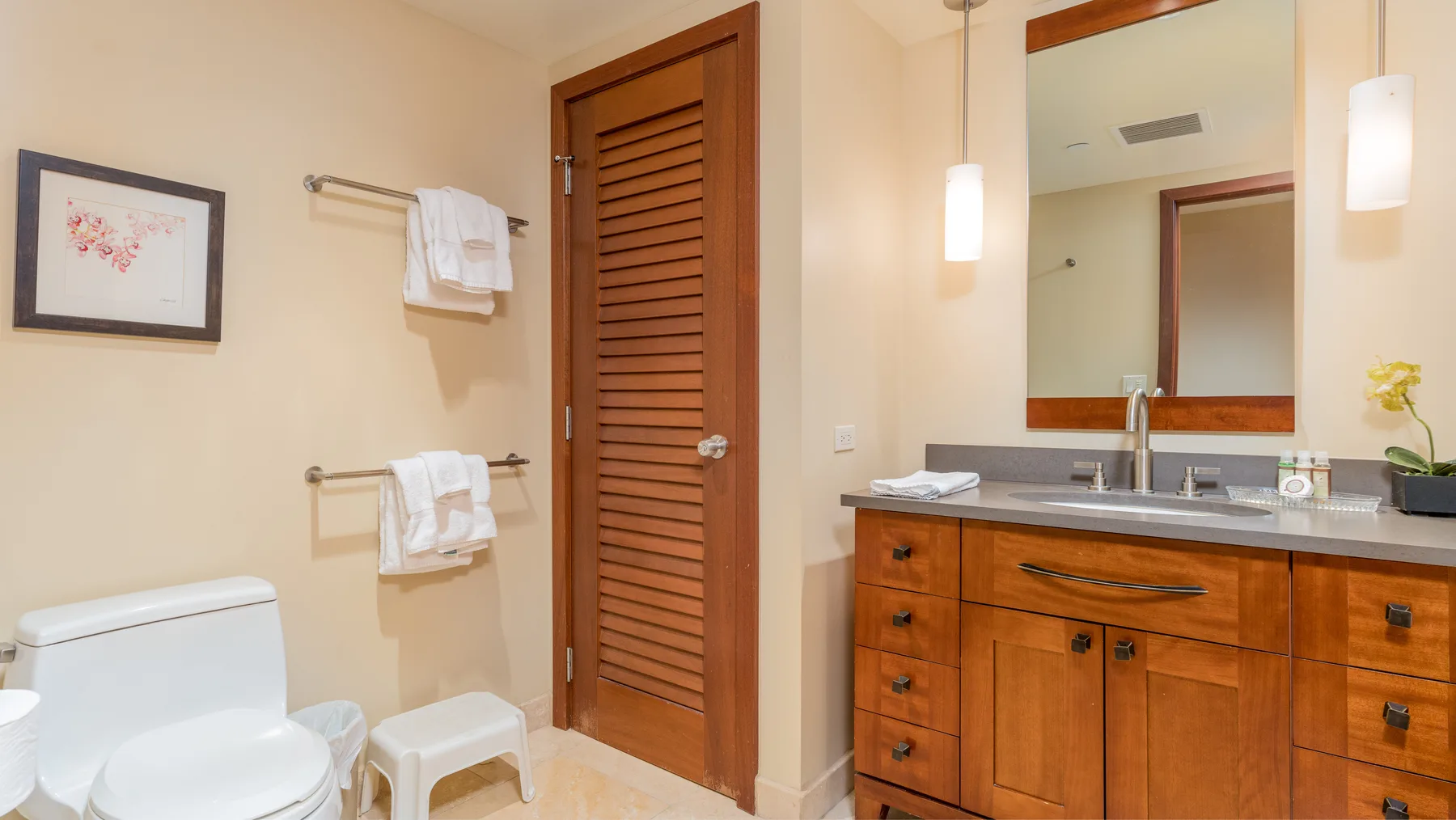 Un baño con un mueble de madera, un espejo y un inodoro.