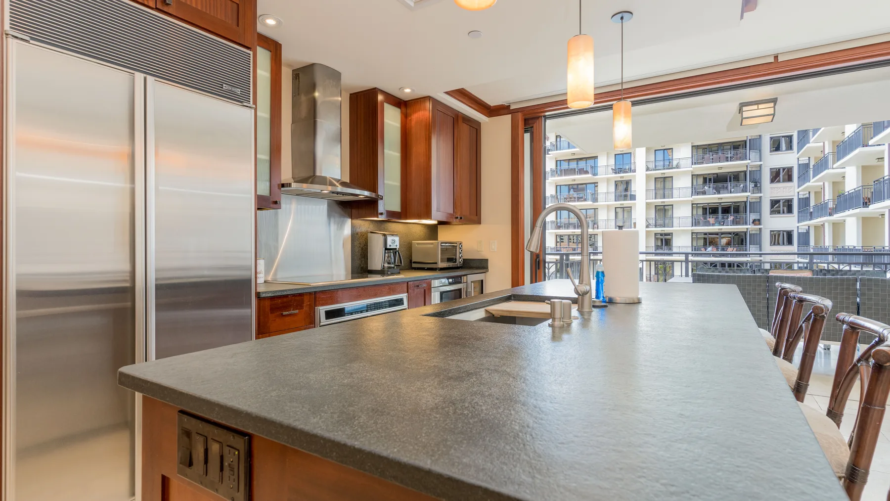 Una cocina moderna con una isla grande y ventanas con vista a edificios cercanos.