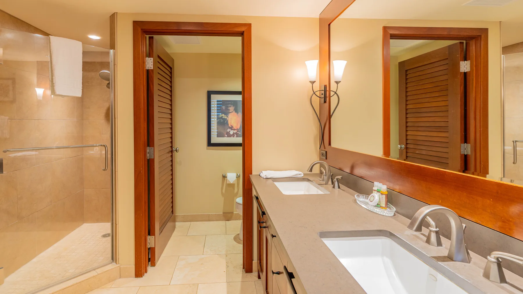 Un tocador de baño con lavabo y espejo junto a una ducha de vidrio.