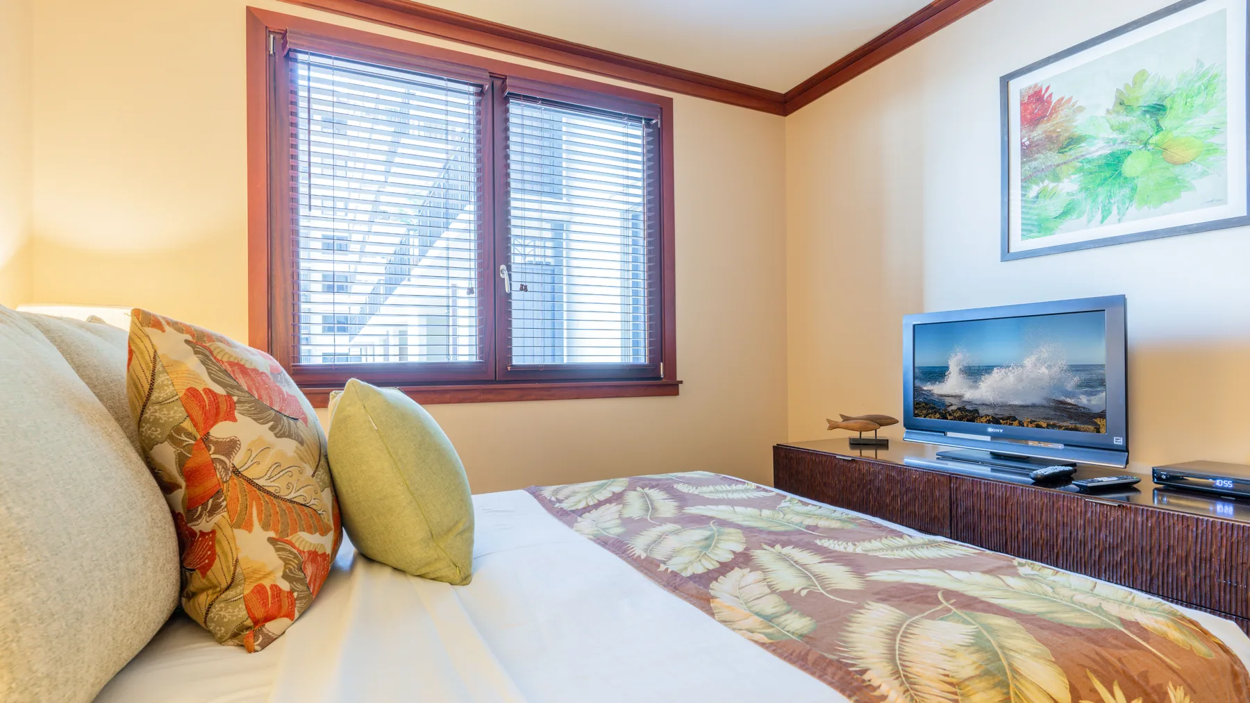 Un dormitorio con una cama, un televisor y una ventana con persianas.