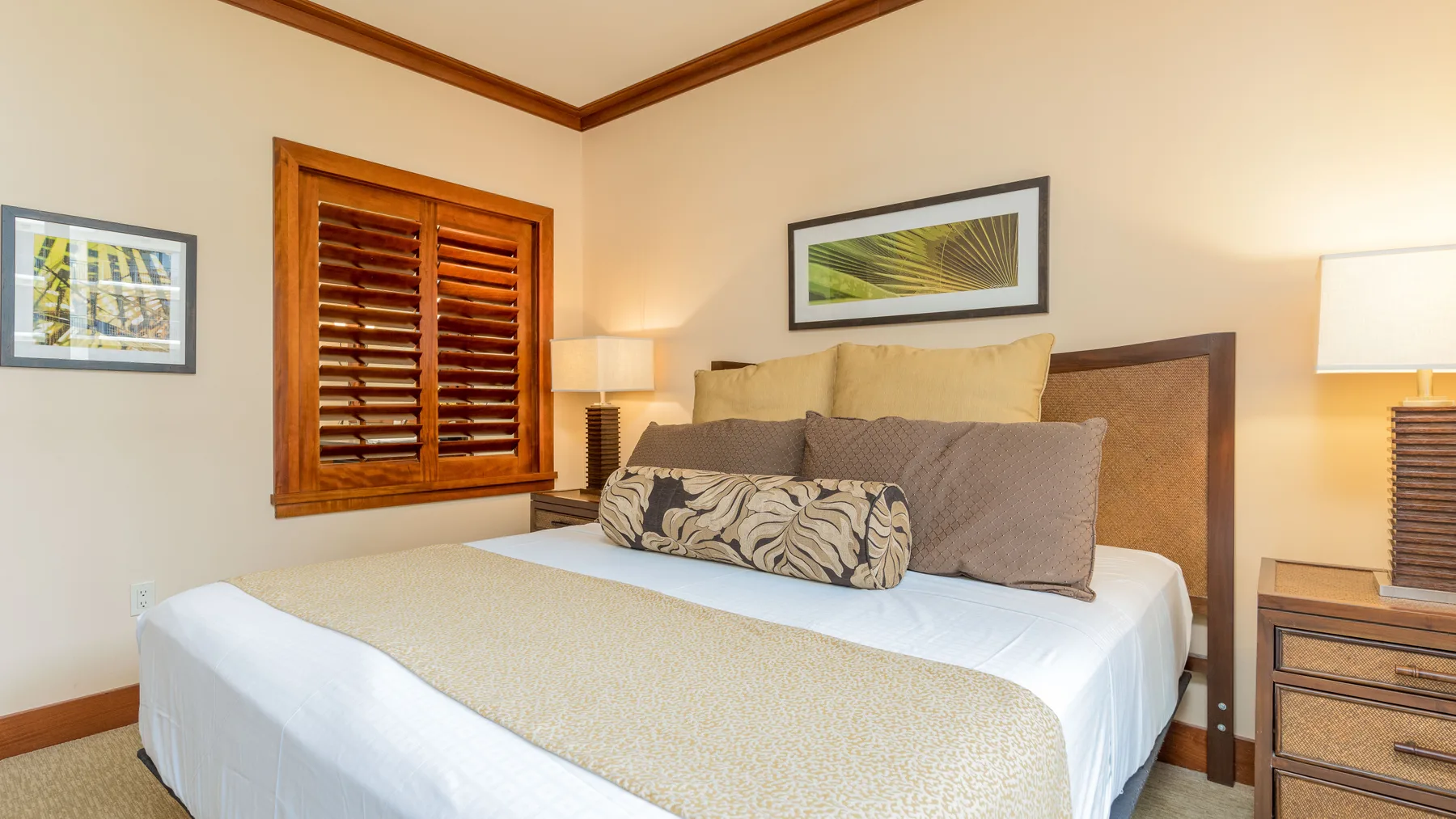 Un dormitorio con una cama bien tendida y cuadros en las paredes.