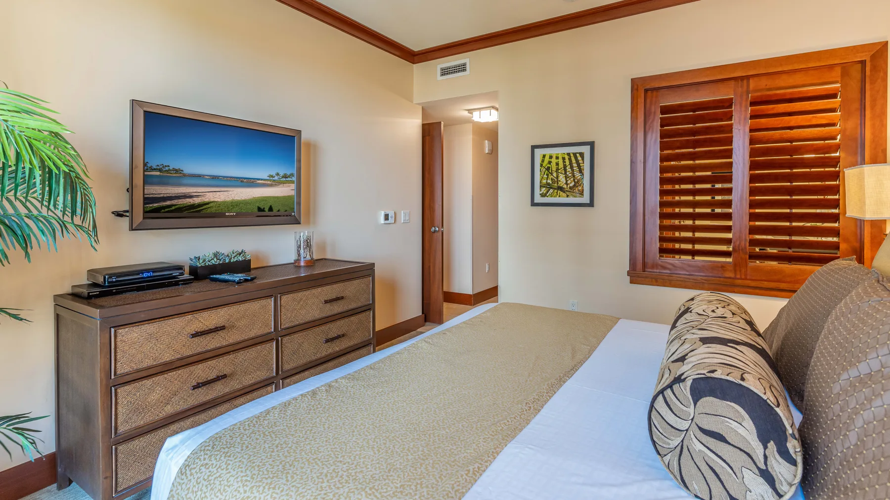 Un dormitorio con una cama, una cómoda de madera y una ventana con persianas de madera.