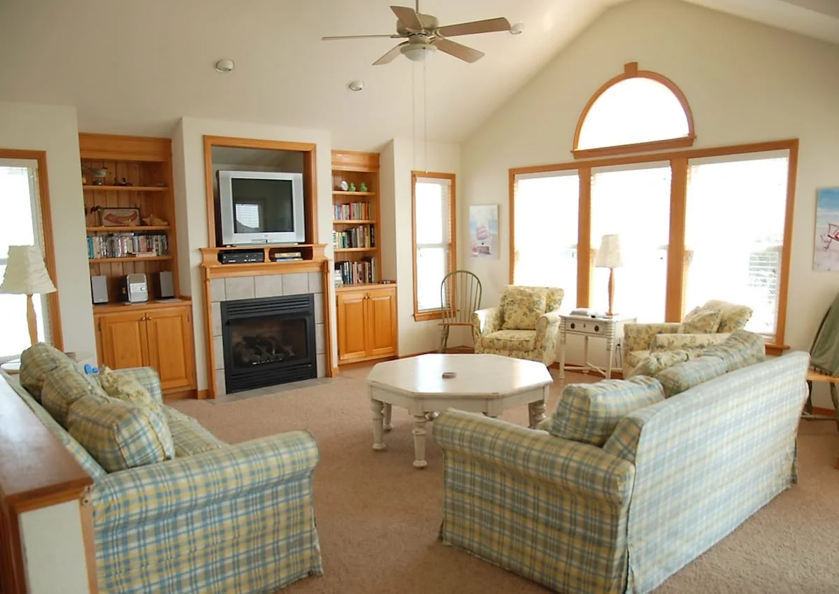 A bright living room with seating, a fireplace, and large windows.