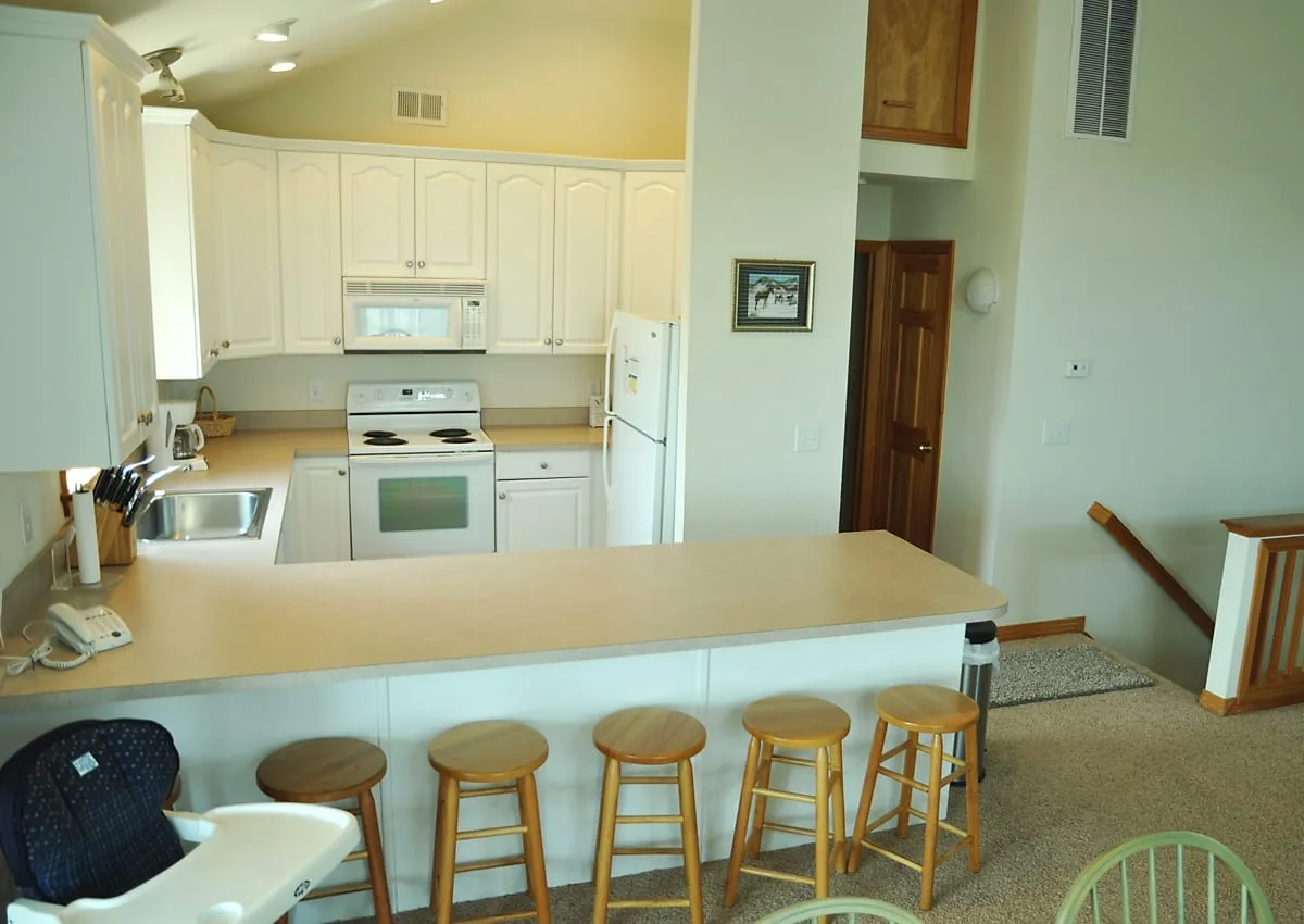 A kitchen with a long breakfast counter and several stools.