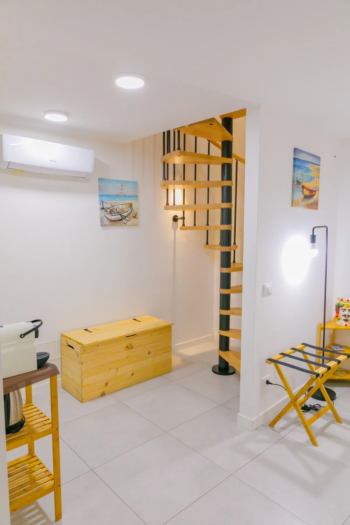 Una habitación luminosa con un baúl de madera y una escalera de caracol.