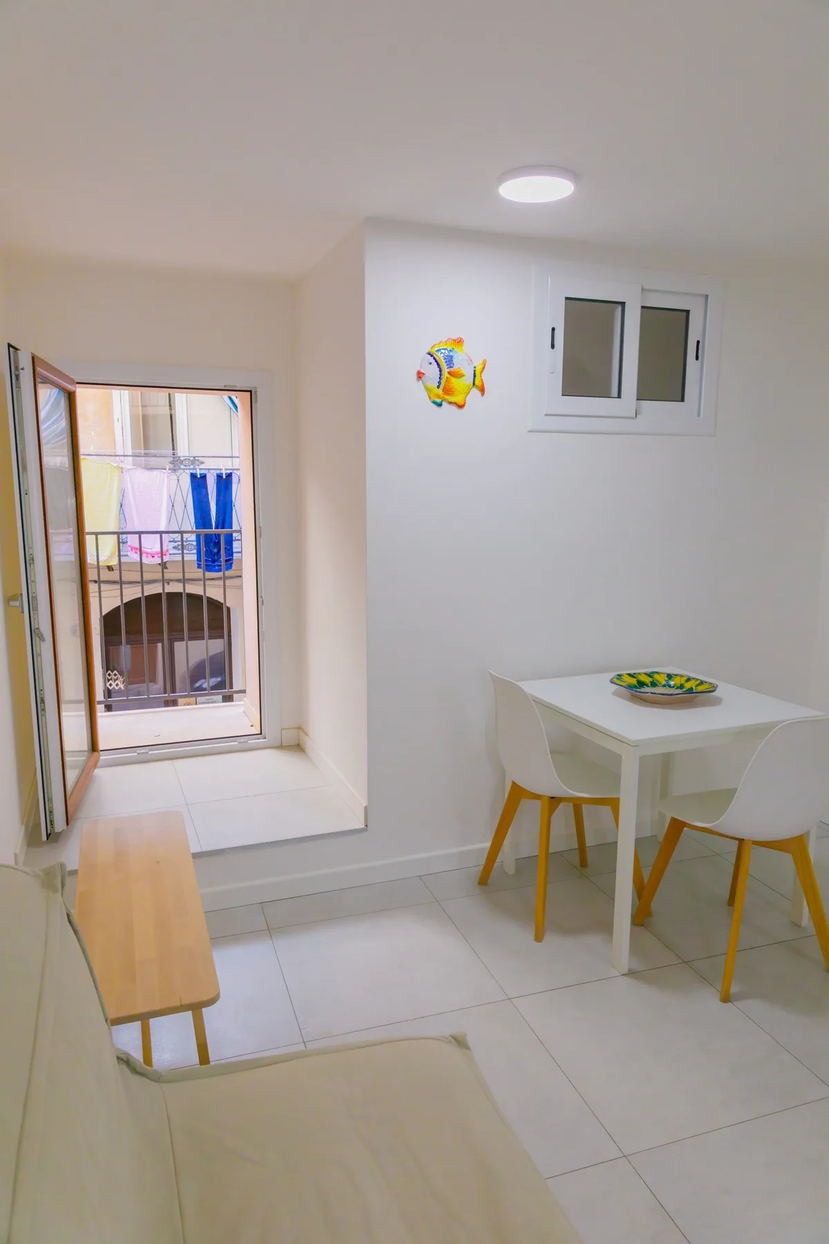 Un pequeño comedor con una mesa y sillas junto a una ventana abierta.