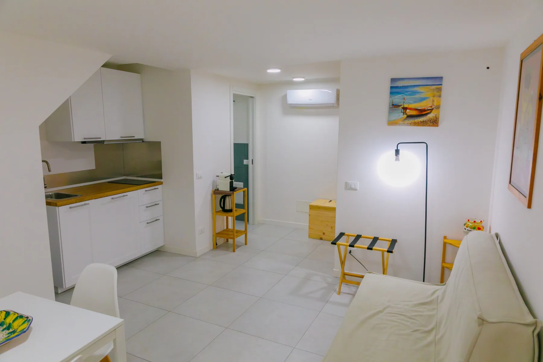 Un estudio luminoso con cocina compacta, asientos y una mesa pequeña.