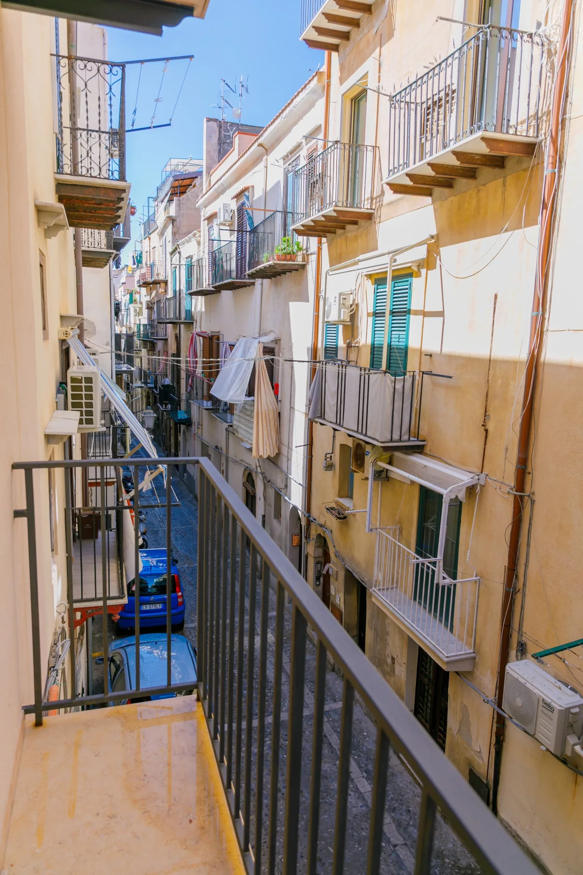 Una calle estrecha bordeada de edificios de apartamentos, vista desde un balcón.