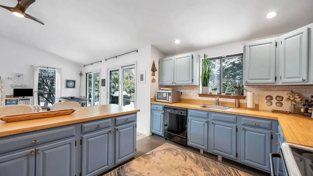 Una cocina luminosa con gabinetes azules, encimeras de madera y una isla central.