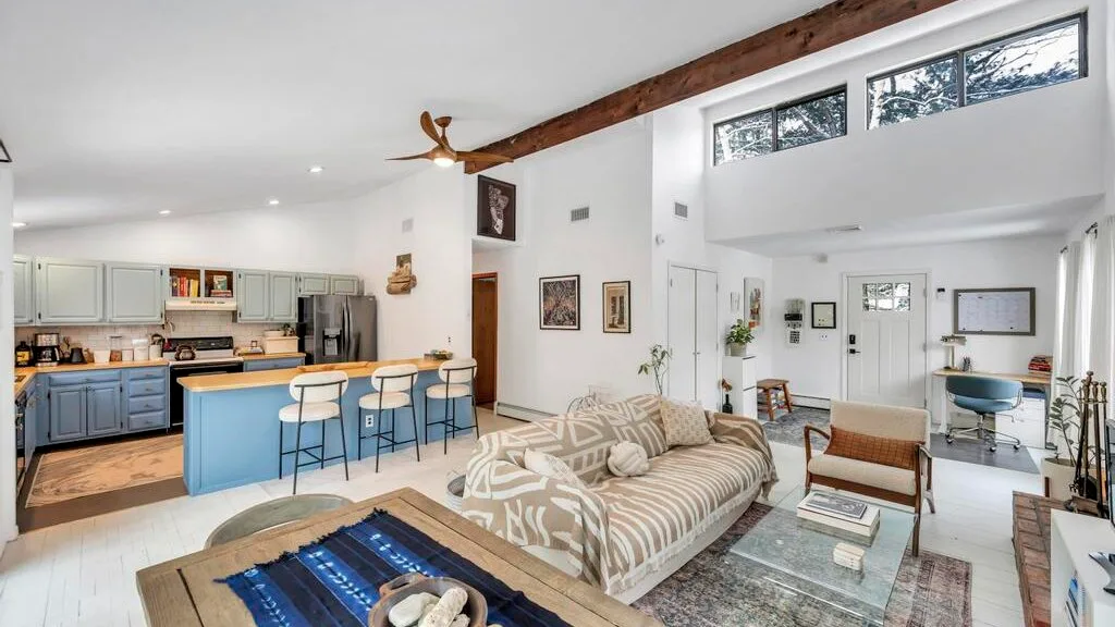 Sala de estar y cocina de concepto abierto con sofá y barra de desayuno.
