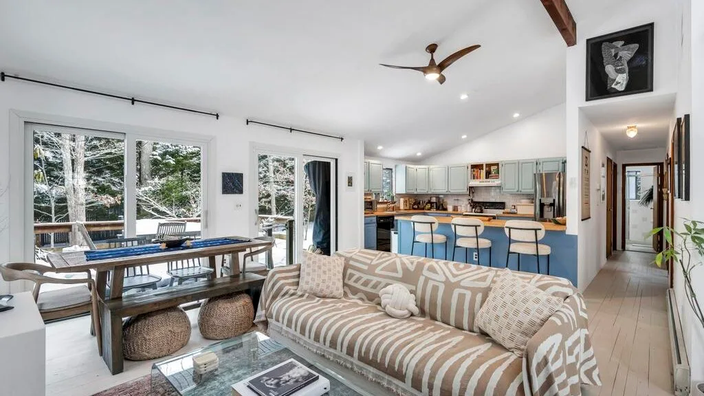 Una sala-comedor de planta abierta tiene un sofá estampado y una cocina con isla azul.