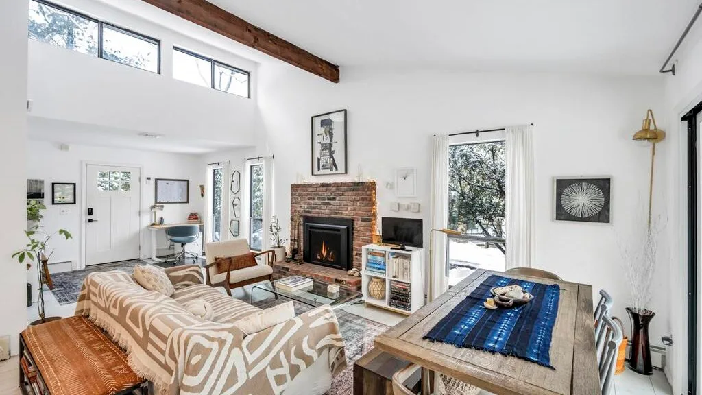 Una luminosa sala de estar con asientos, una chimenea de ladrillo y una mesa de comedor.