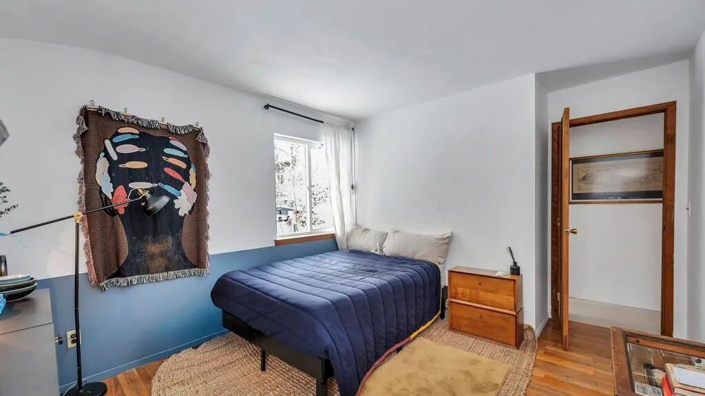 Un dormitorio con una cama junto a una ventana y una cómoda de madera.