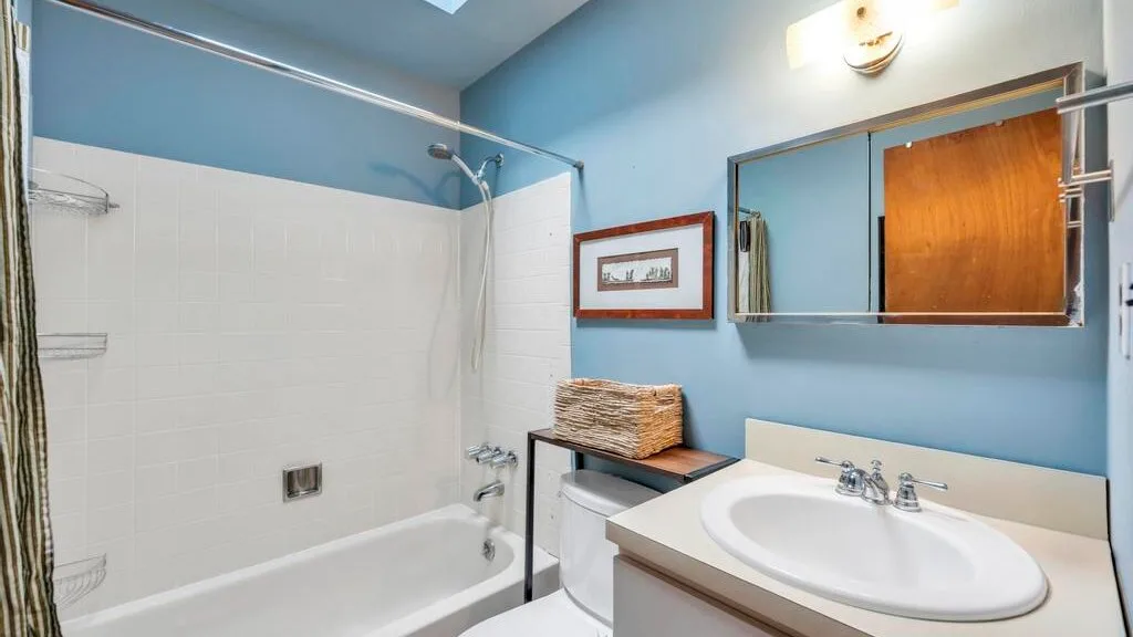 Un baño con bañera, ducha y lavabo bajo un espejo de pared.