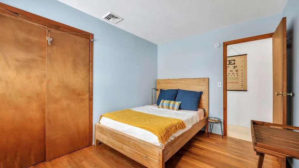 Un dormitorio con una cama de madera, ropa de cama colorida y un armario.