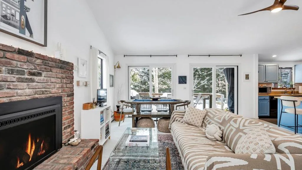 Sala de estar con chimenea de ladrillo, asientos estampados y zona de comedor.