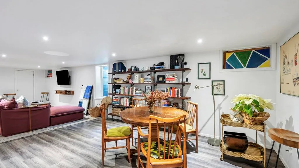 Una sala de estar y comedor con asientos, una mesa de madera y estanterías abiertas.