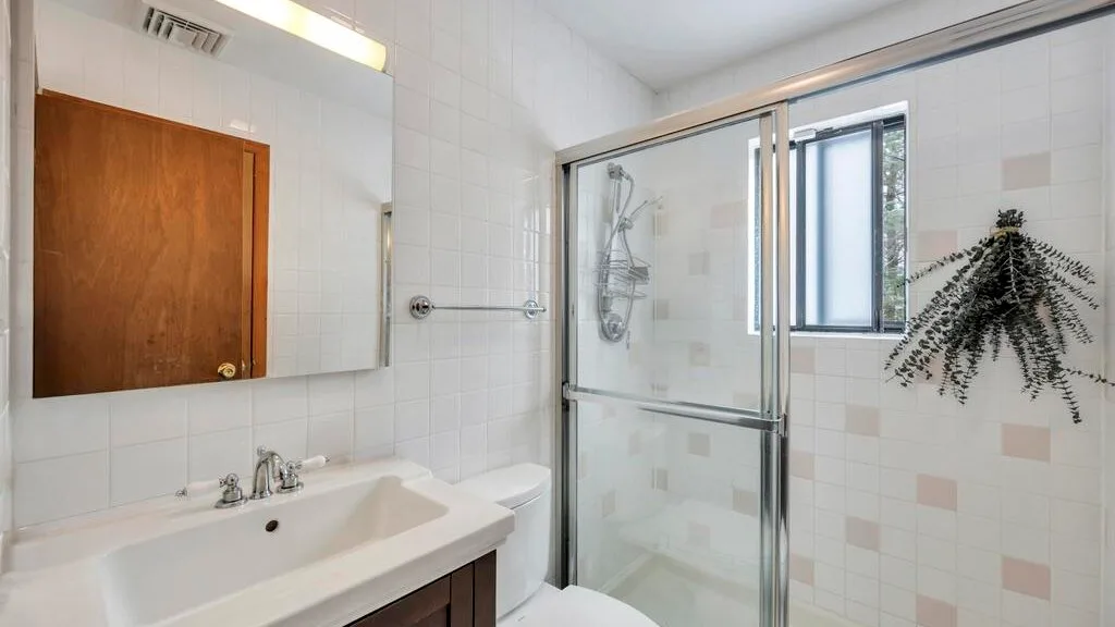 Un baño alicatado con lavabo y ducha con mampara de vidrio.