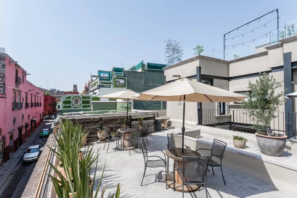 Rooftop terrace with dining area, umbrella shade, and views of colorful colonial buildings