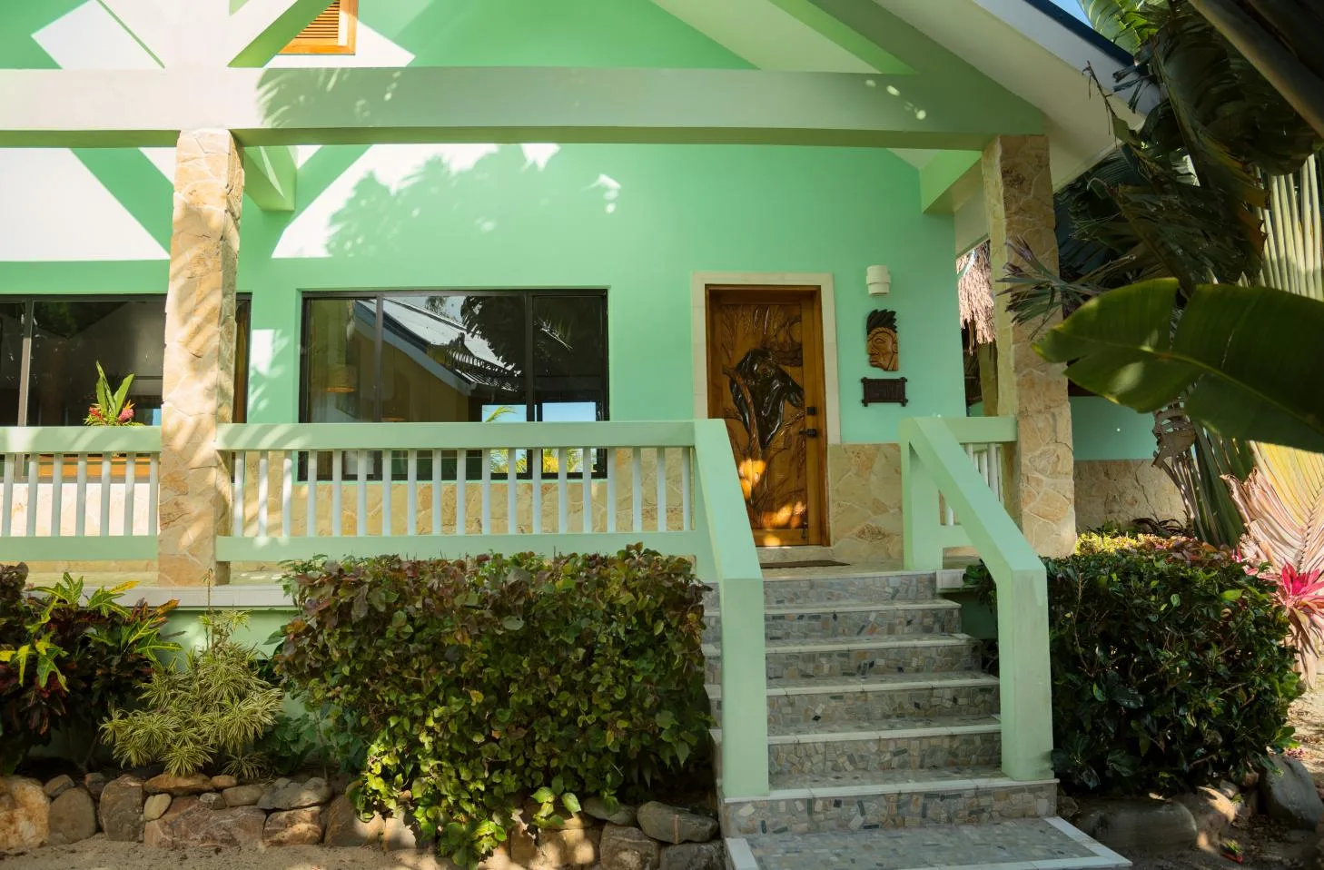 A mint-green house entrance has a short staircase and a wooden door.