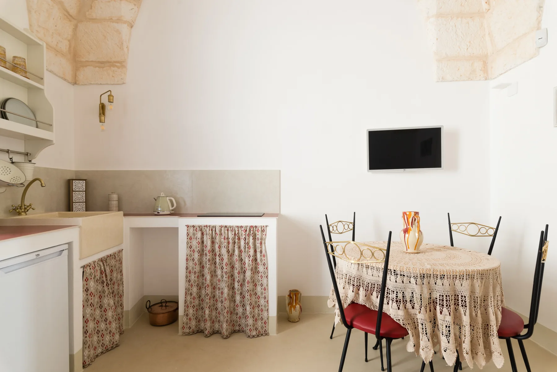 A dining area with a round table and chairs sits beside a small kitchen.