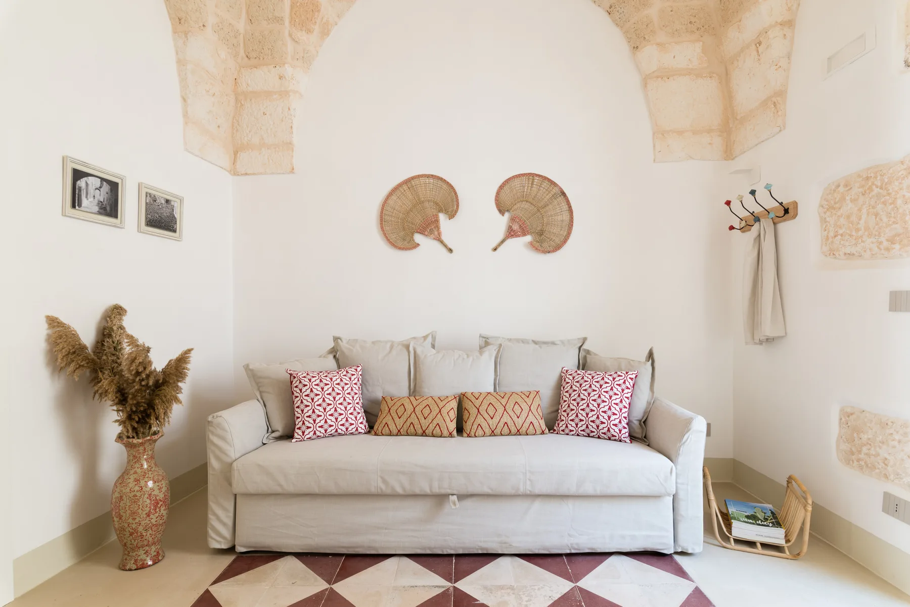 A bright sitting room with a light-colored sofa beneath a stone arch.