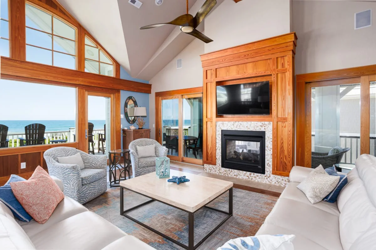 A bright living room with seating arranged around a fireplace and television.