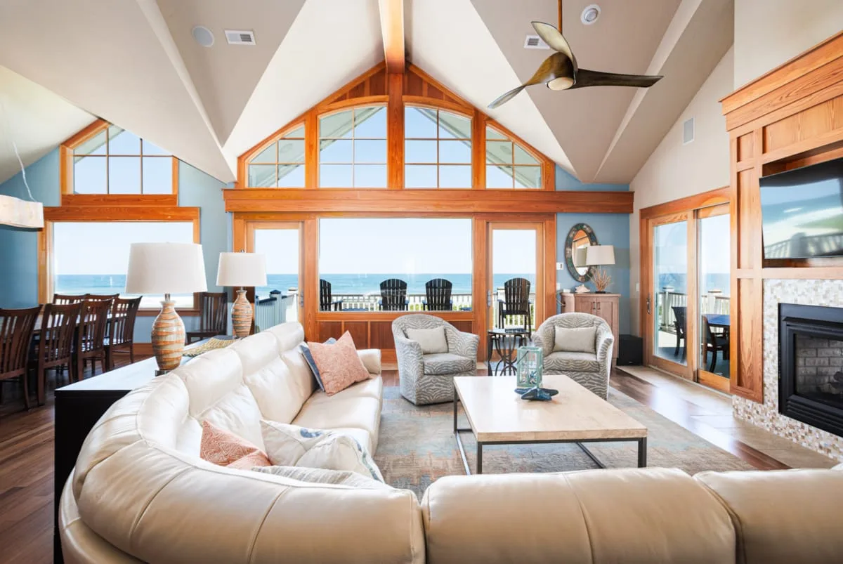 A bright living room with seating beside large windows overlooking the water.
