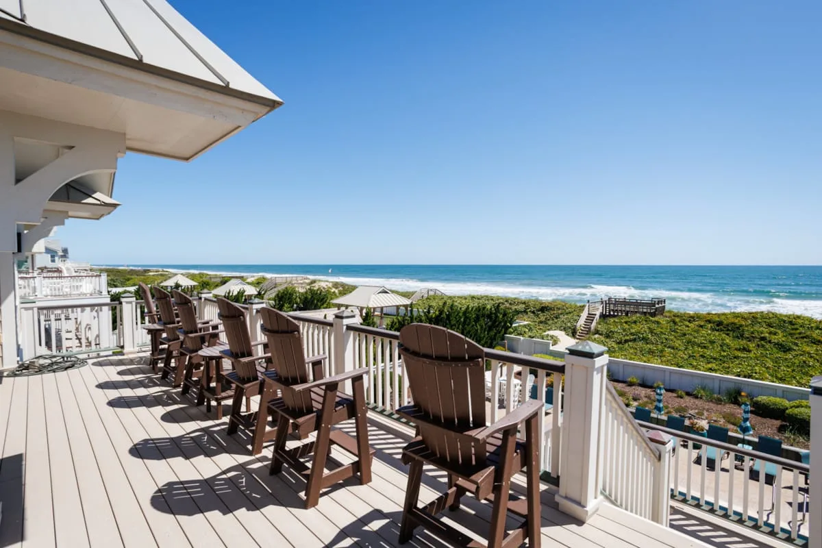 A seaside deck with outdoor seating overlooks the ocean.