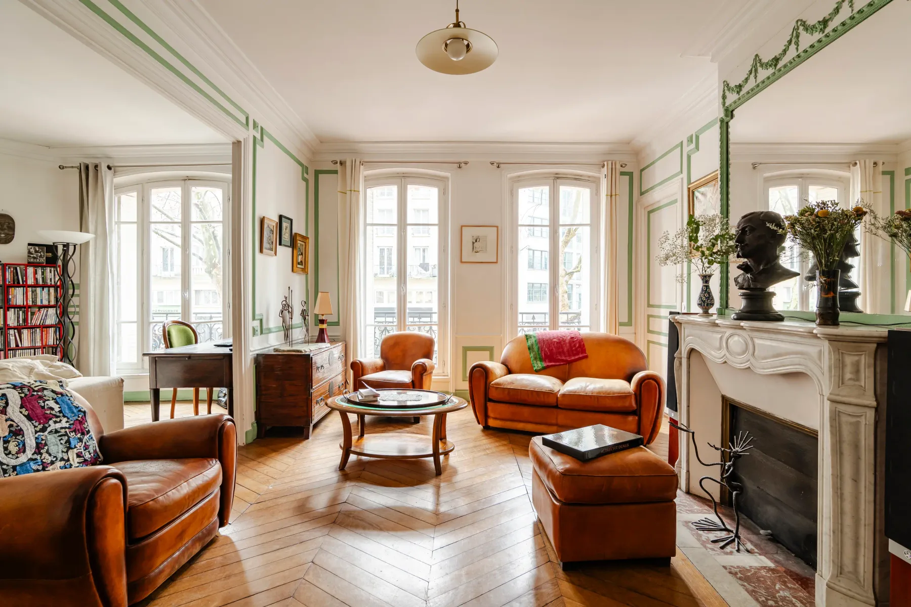 A living room with orange seating, tall windows, and a fireplace.