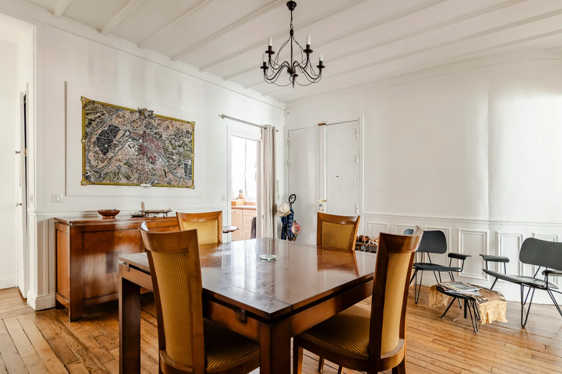 A bright dining room with a large wooden table, chairs, and wall art.