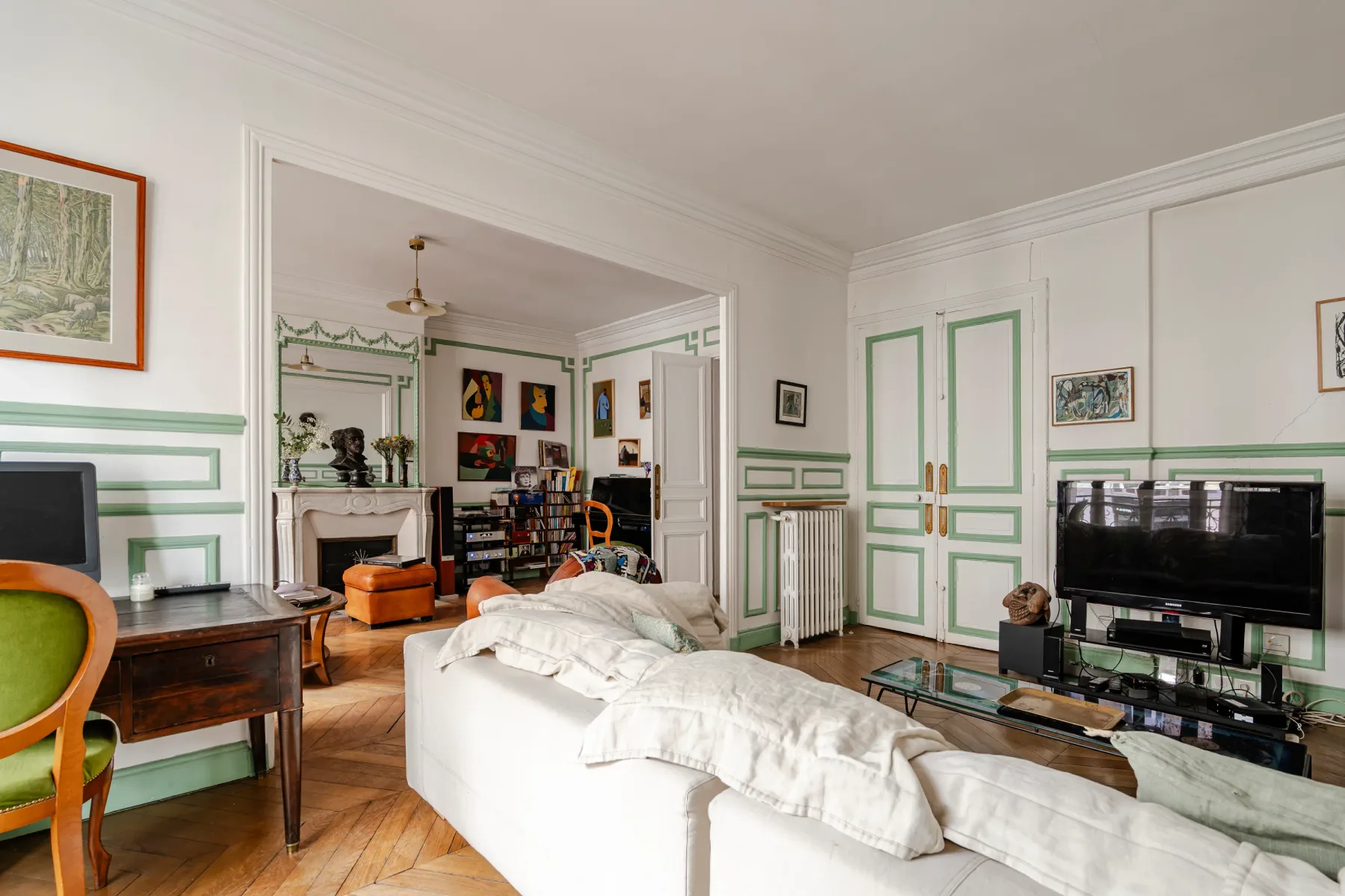 A bright living room with green-trimmed walls and white seating.